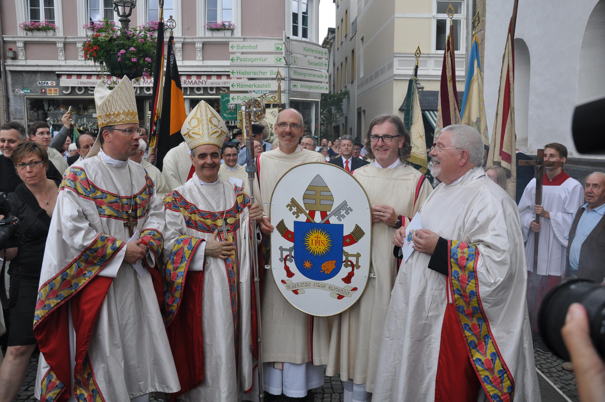 19.07.2015: Das Wappen von Papst Franziskus wird von Bischof Stephan Ackermann und dem Nuntius des Papstes an Pfr. Ludwig und die neue Basilika überreicht